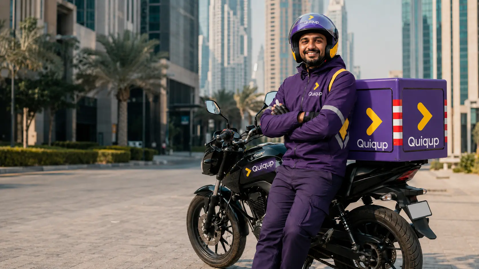 Representative South Asian delivery rider wearing Quiqup-branded equipment beside a Quiqup-branded motorcycle